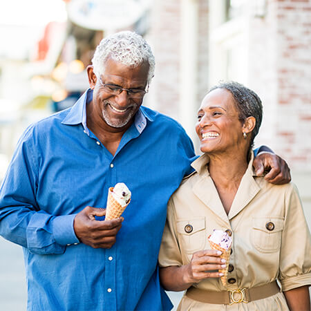 An older couple walking down the street with icecream cones