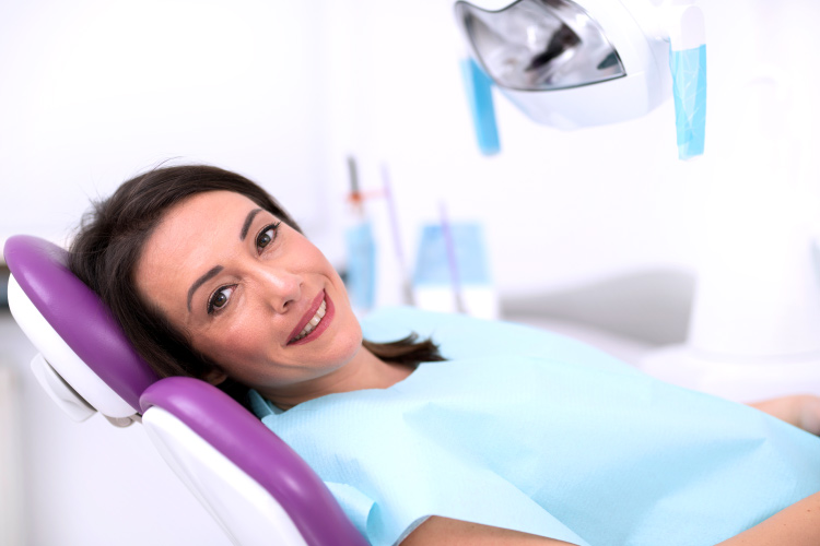 Smiling brunette woman in the dental chair ready for a dental implant
