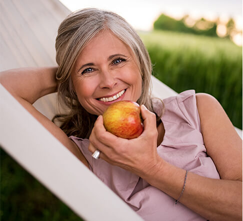 smiling senior woman holding an apple